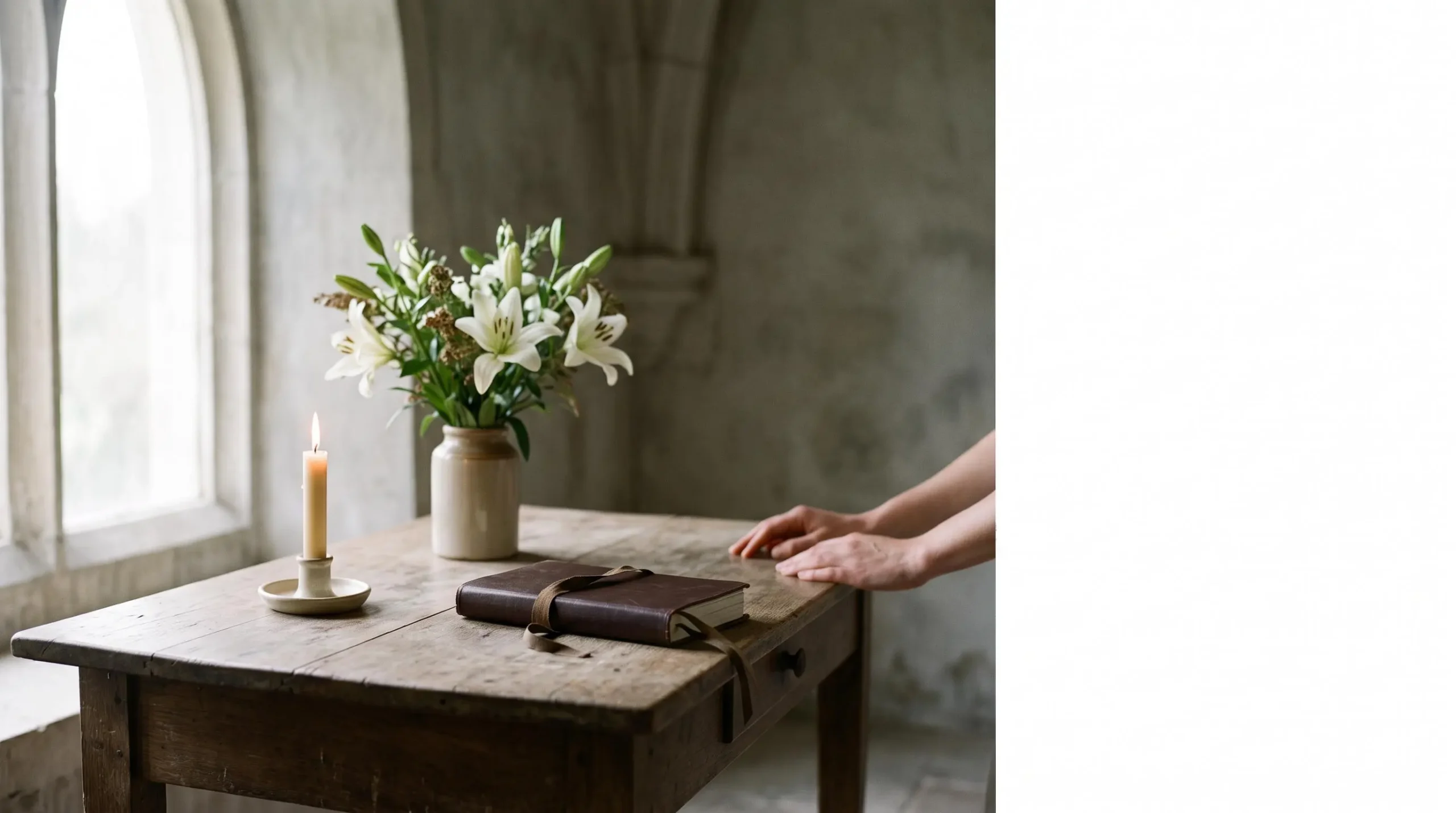 Table en bois avec une bougie allumee, des fleurs blanches et un carnet ferme, symbolisant l'organisation sereine et methodique des obseques